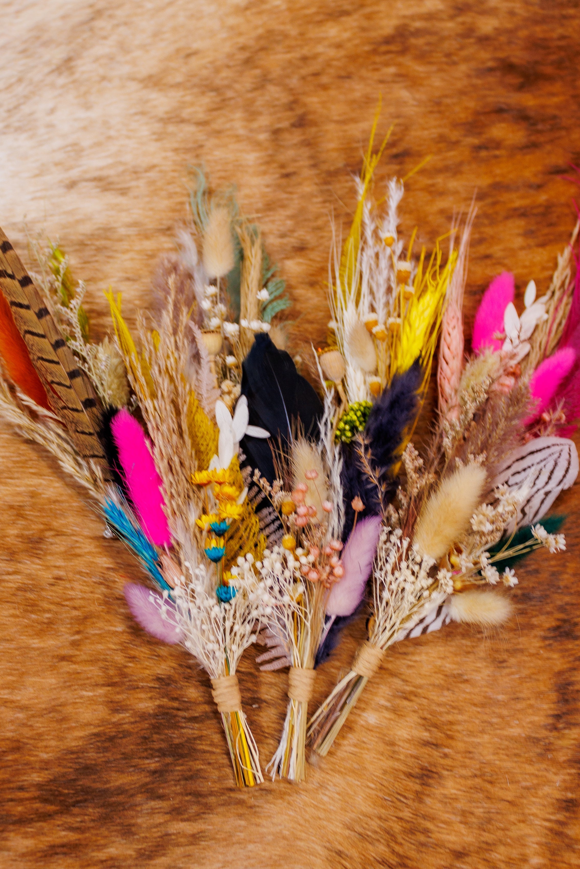 colorful hat pins with dry florals, grass, and feathers
