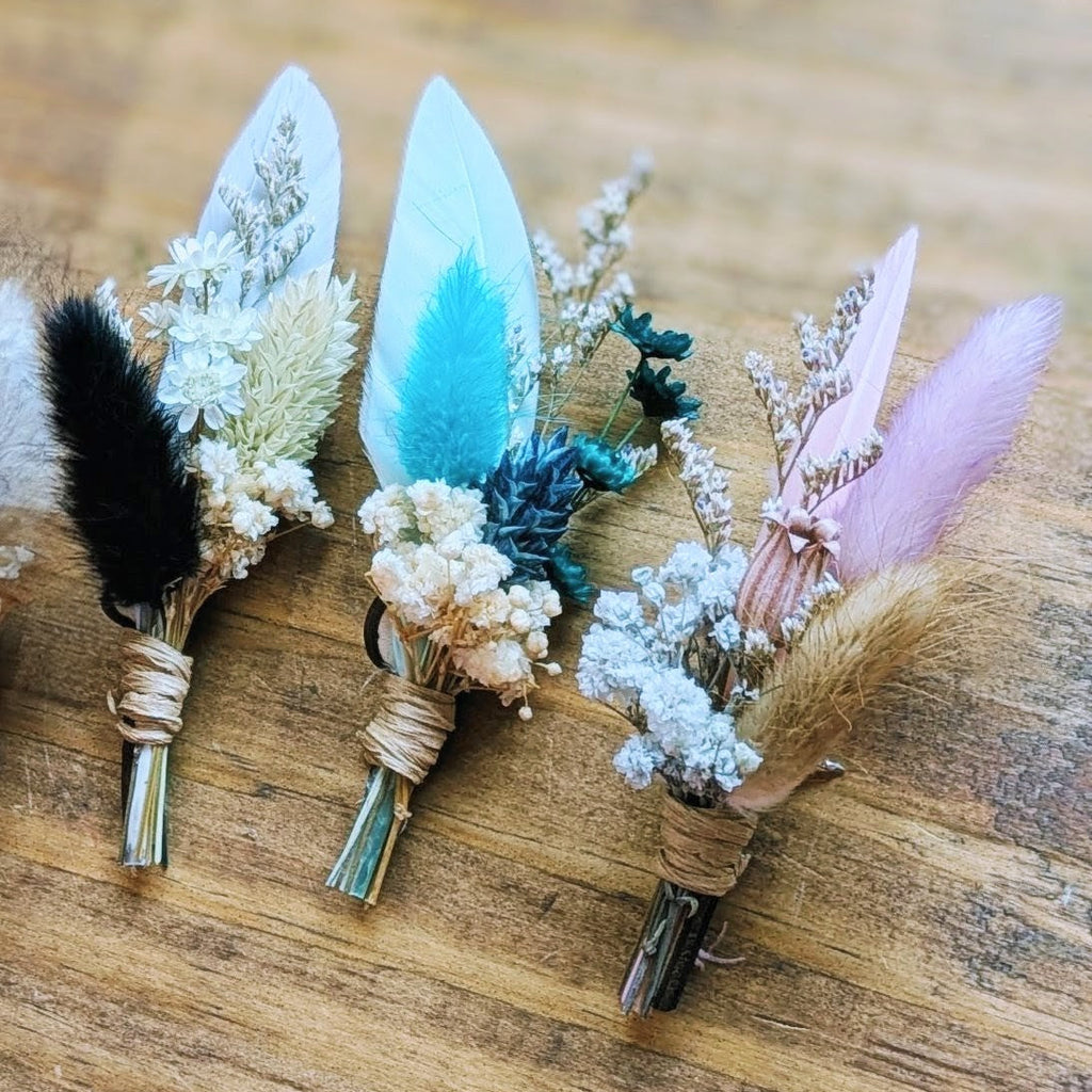 Three BittyBud hat pins: black bunny tail with white florals, light blue feather with teal, and pink feather with lavender