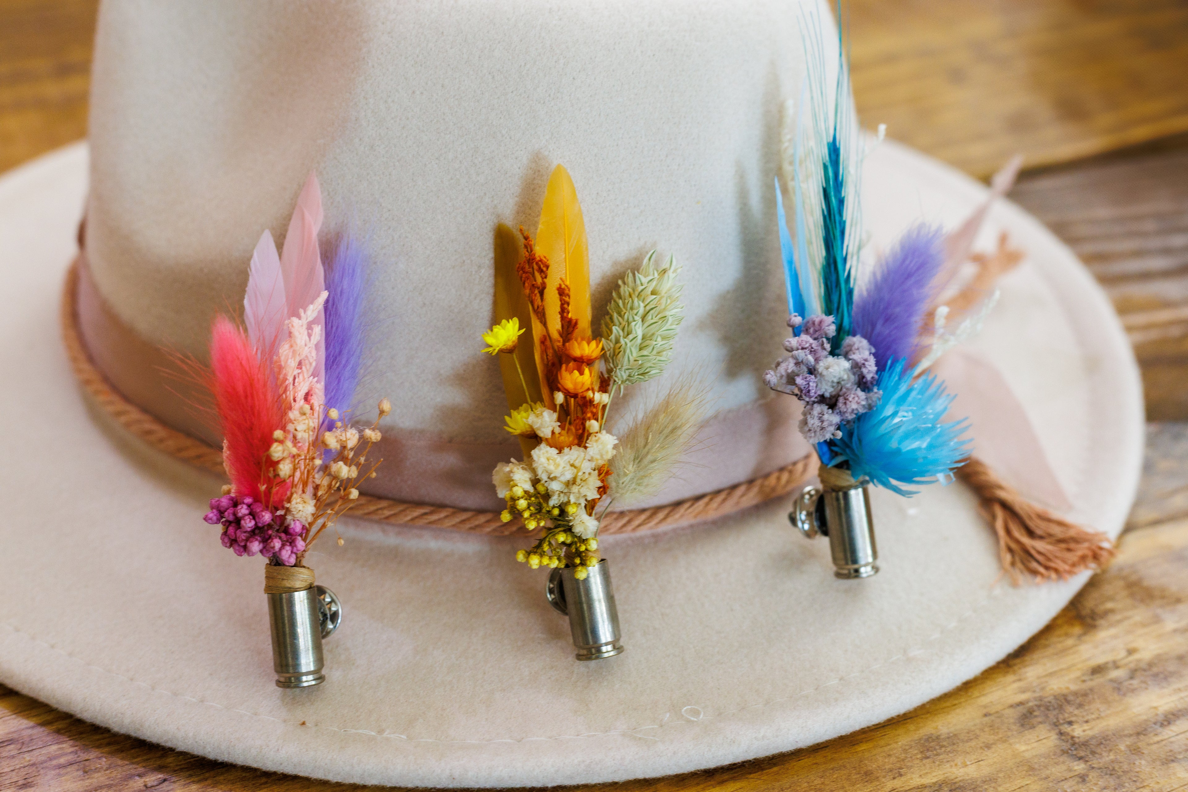 White hat with colorful feather and flower decorations on a wooden surface