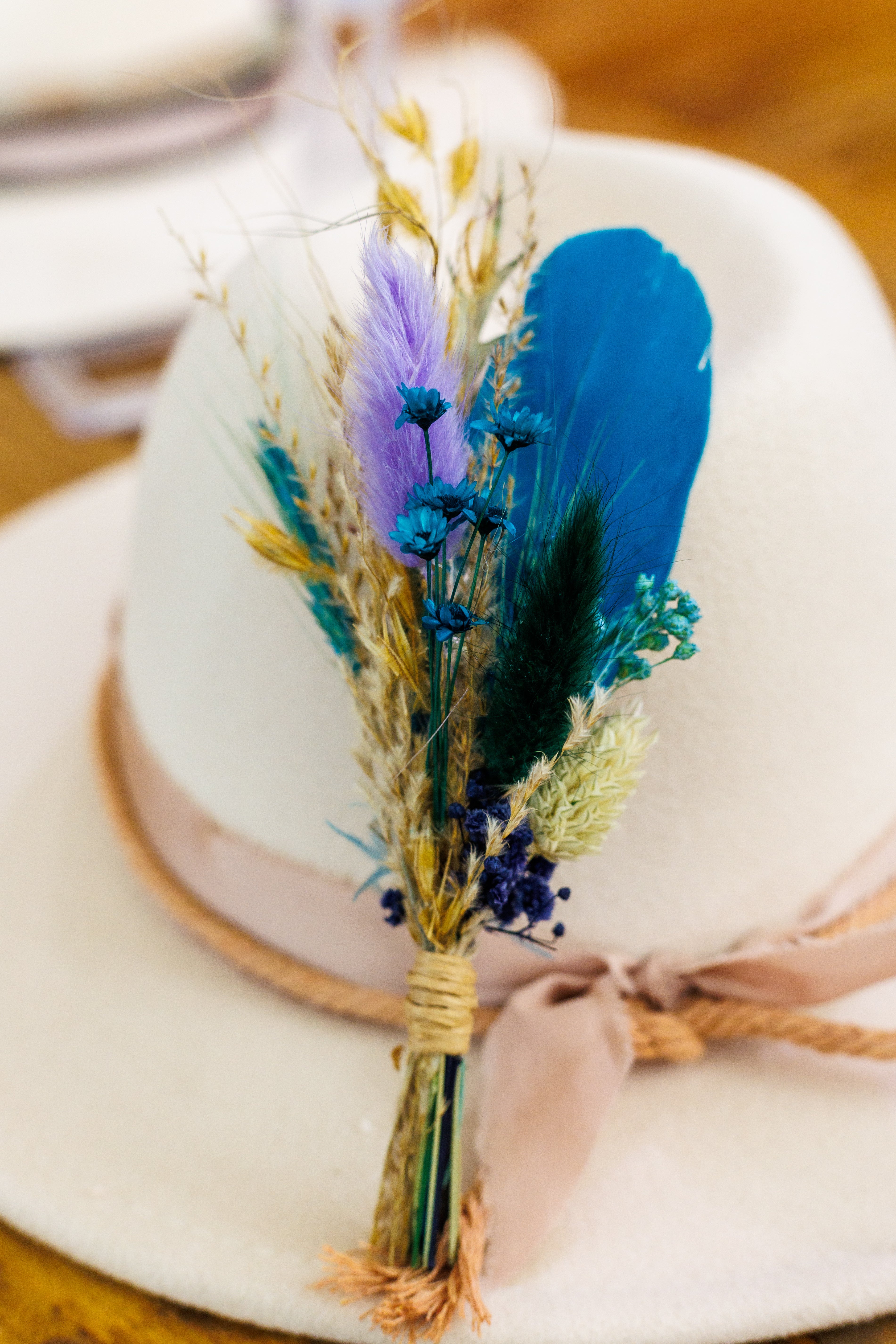 White hat with a decorative feather and ribbon bow on a wooden surface
