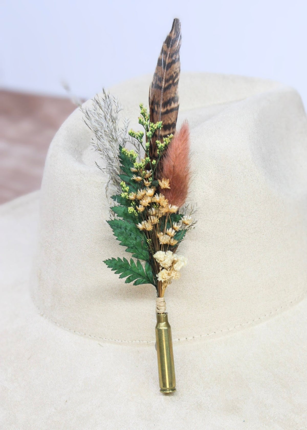 Bullet BrimBud hat pin Copper with barred pheasant feather, rust bunny tail, and peach florals on a cream felt hat