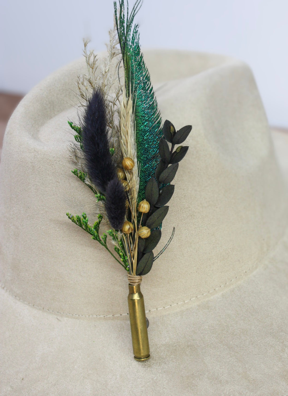 Bullet BrimBud hat pin Emerald with iridescent green peacock feather, navy tails, and gold berries on a cream felt hat