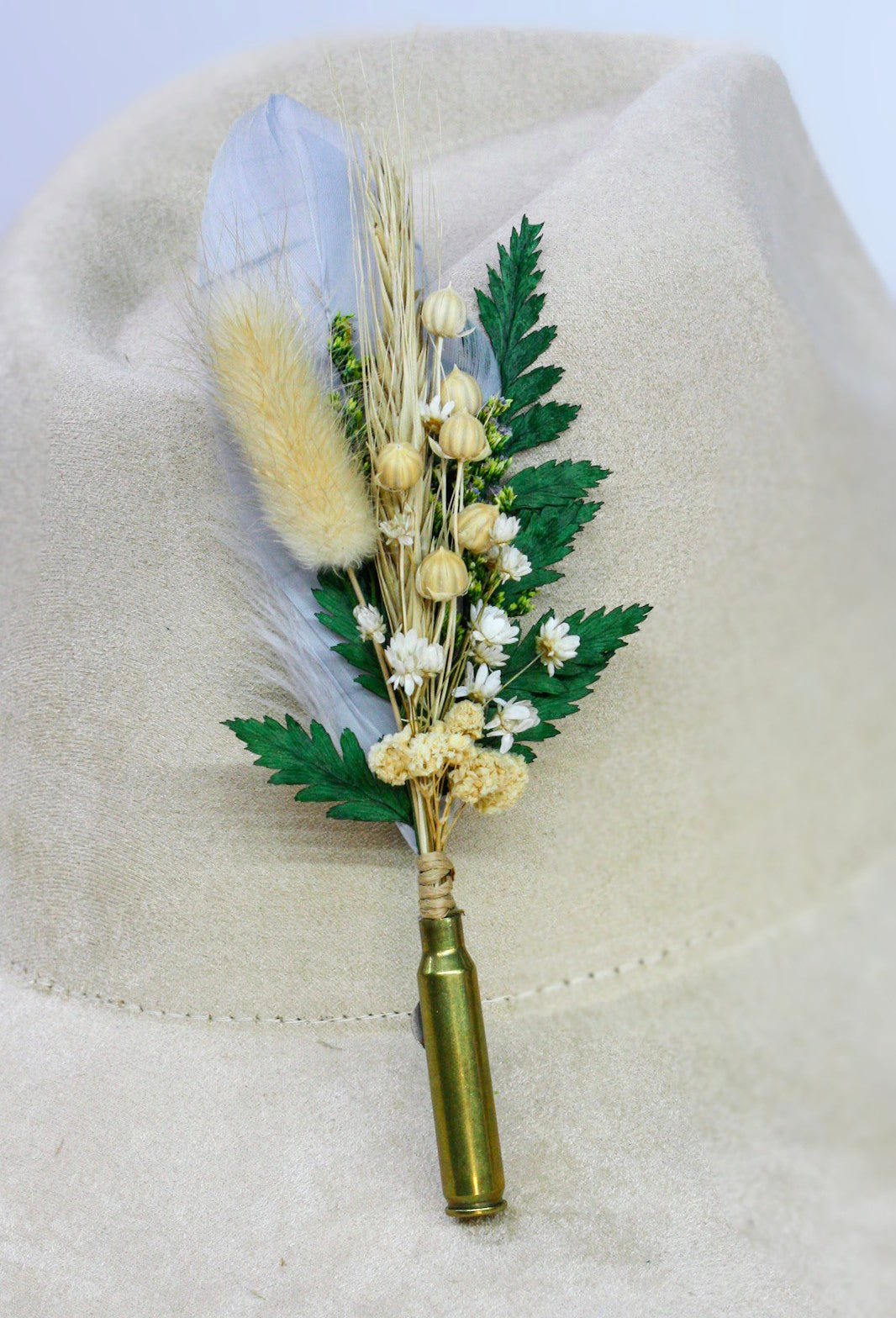 Bullet BrimBud hat pin with pale blue-white feather, tan bunny tail, and green fern on a cream felt hat