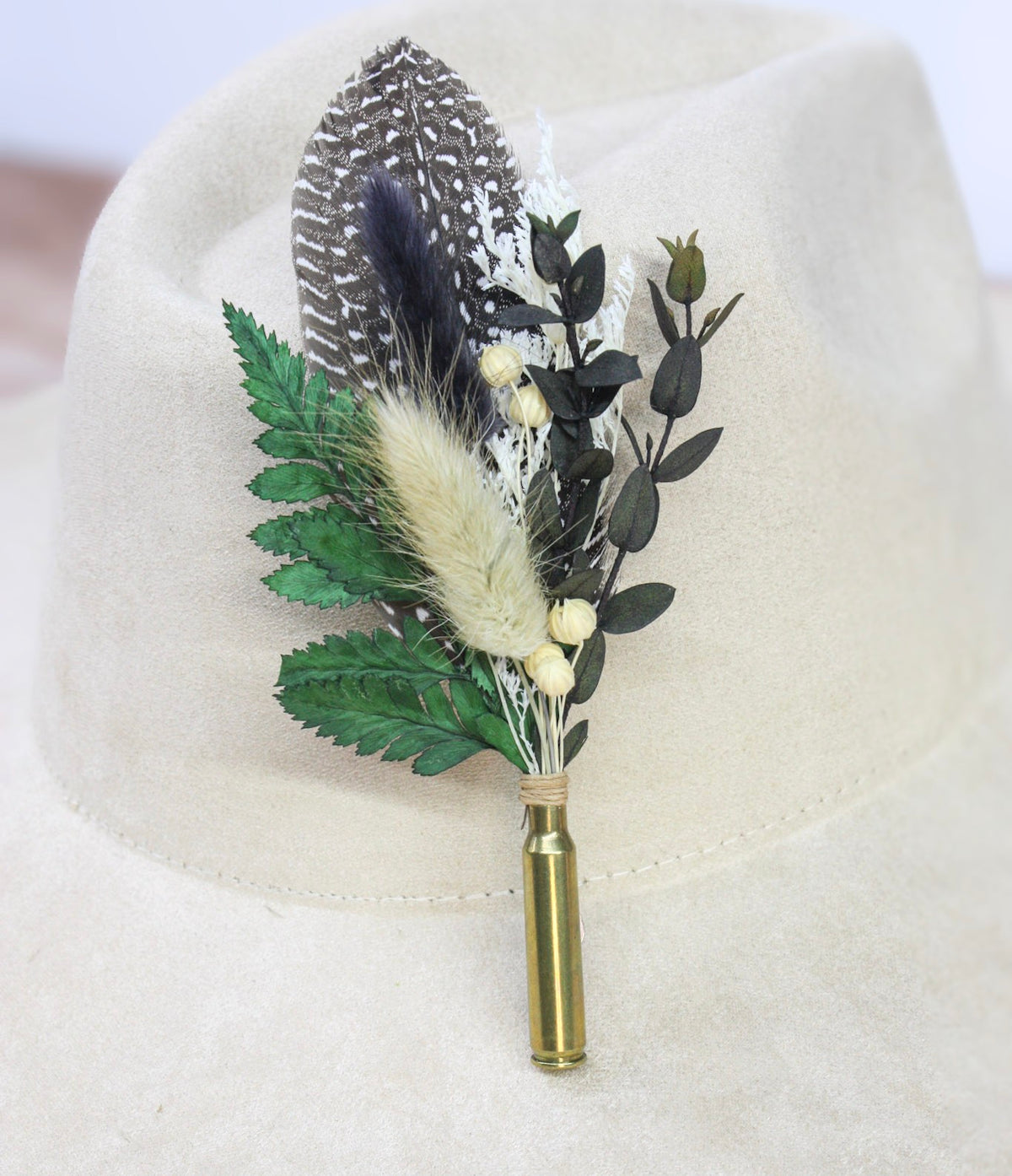 Bullet BrimBud hat pin Pepper with spotted guinea hen feather, green fern, and cream bunny tail on a cream felt hat