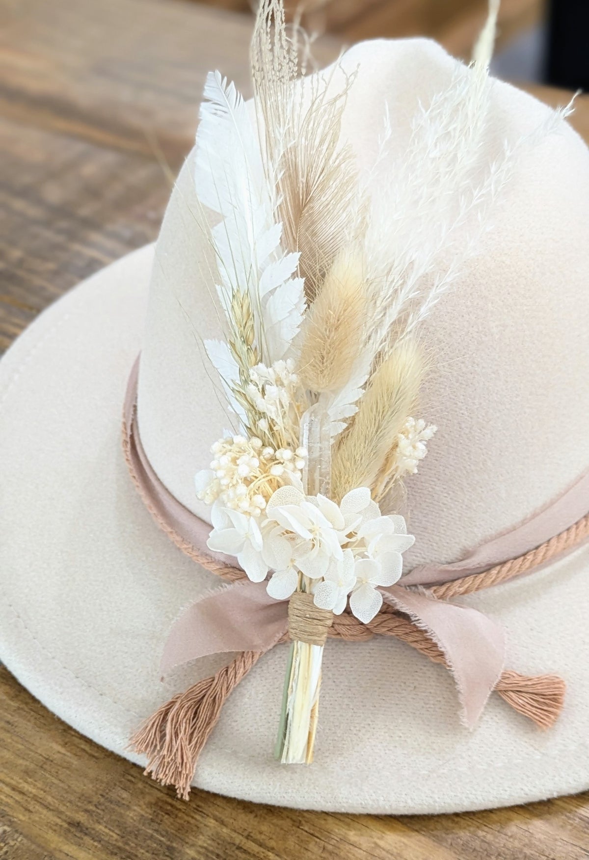 Premium Bridal BrimBud hat pin with white and cream florals, white feathers, and blush ribbon on a cream felt hat