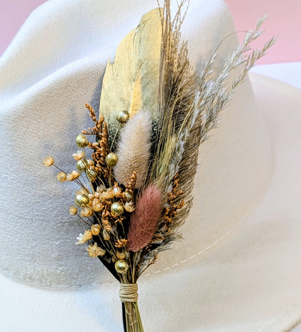 Premium BrimBud hat pin The Lainey with gold feather, golden dried florals, and mauve bunny tail on a cream felt hat