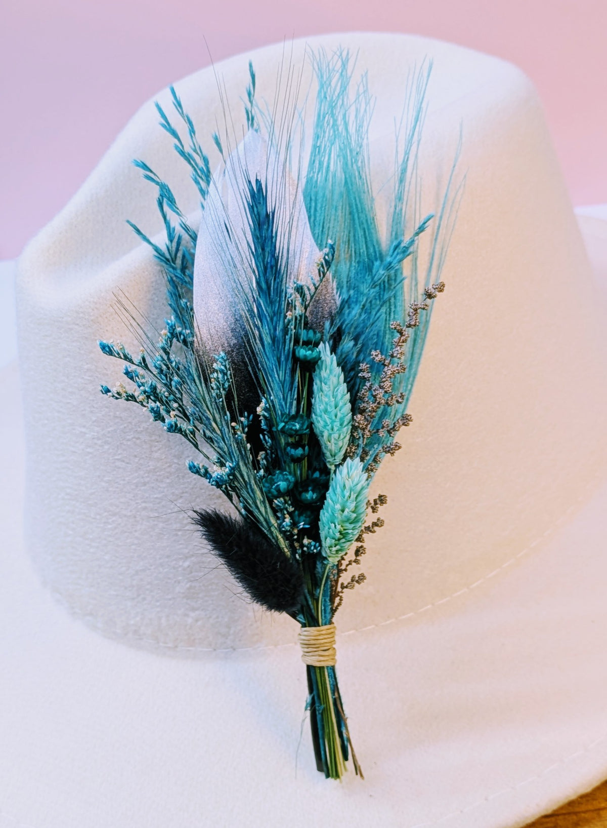 Premium BrimBud hat pin The Reba with teal feathers, teal grasses, and black bunny tail on a cream felt hat