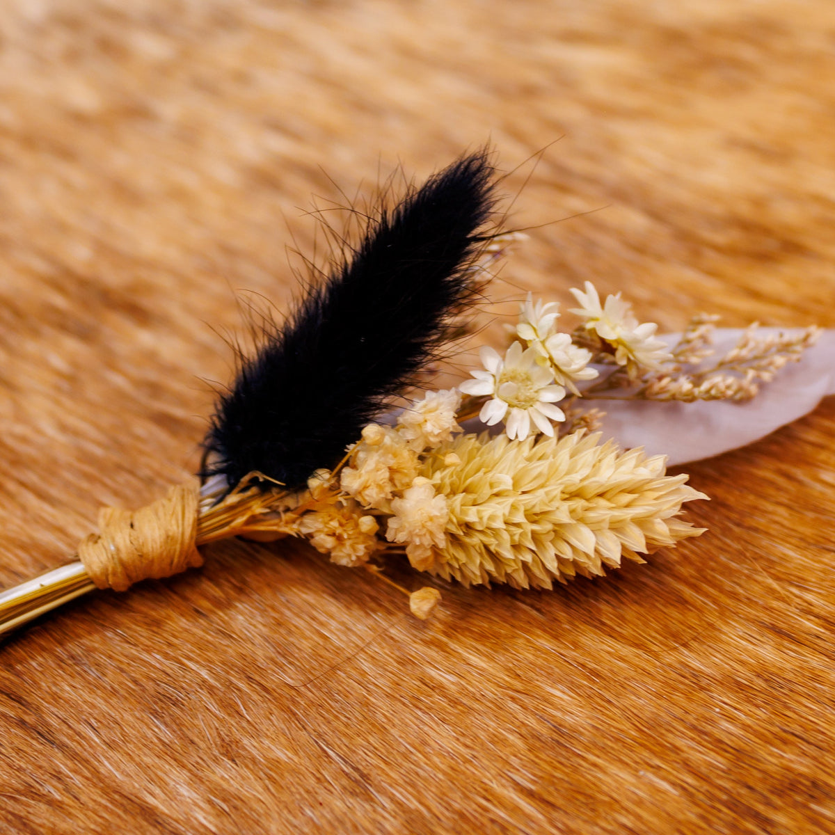 BittyBud hat pin with a black bunny tail, cream wheat, white daisy-like florals, and a white feather
